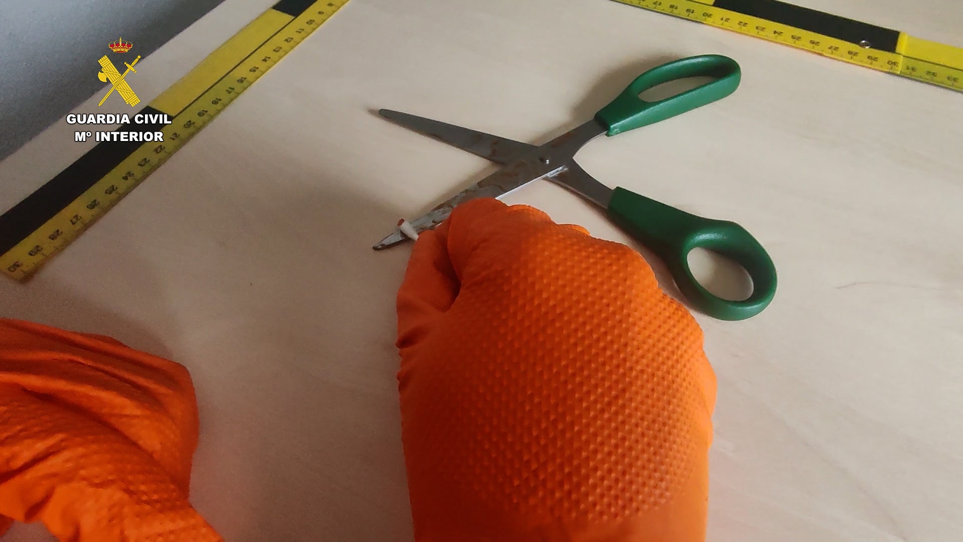 Arriba, la tijera, presunta arma del delito. Abajo, la camiseta con restos de sangre hallada en la vivienda de los presuntos autores.