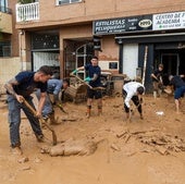 Varias personas limpian una calle en Catarroja, tras la dana.