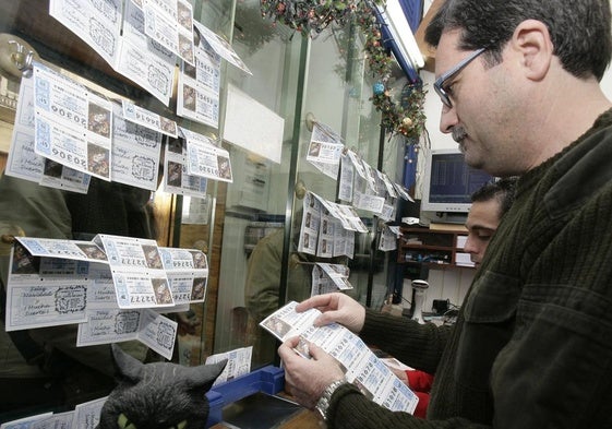 Varias personas compran décimos de lotería de Navidad en una administración de loterías.