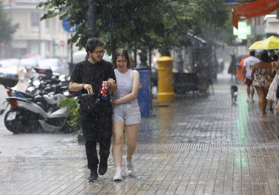 Dos personas se refugian de la lluvia este sábado.