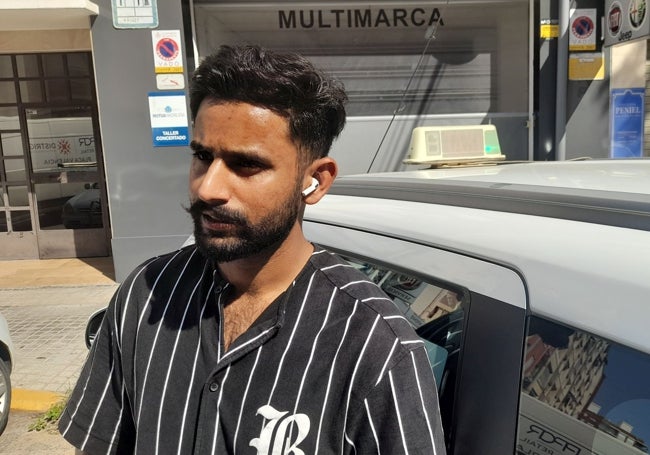 El taxista pakistaní Abdul Ahad, junto a su vehículo.