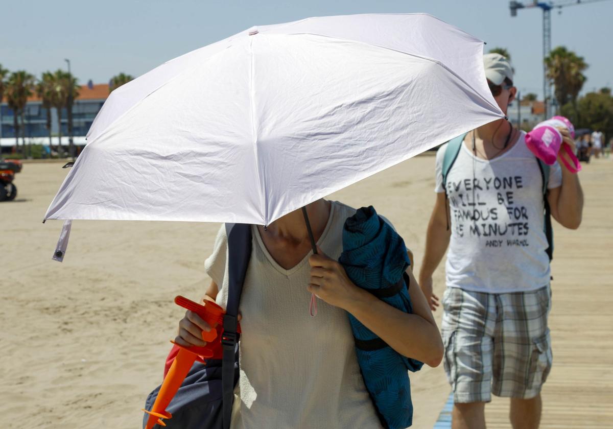 Una mujer se proteje del sol con una sombrilla en Valencia.