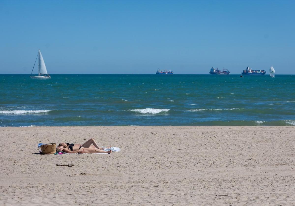 Dos mujeres toman el sol en la playa de Pinedo.