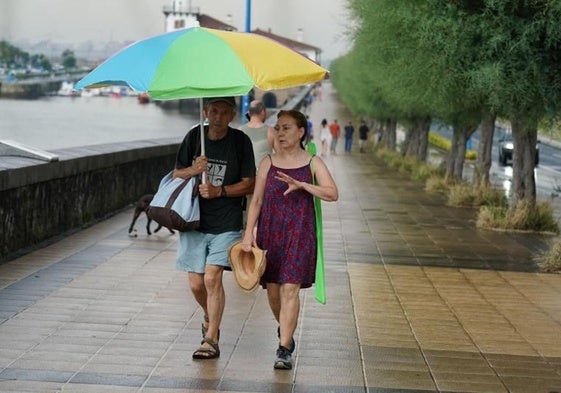 Dos bañistas abandonan la playa por las lluvias.