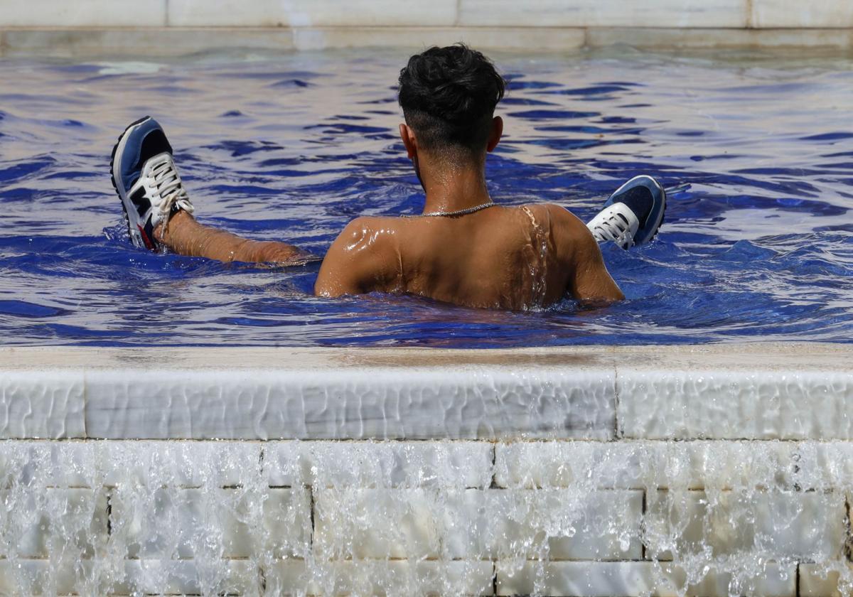 Un joven se refresca debido a las altas temperaturas de este domingo en la ciudad.