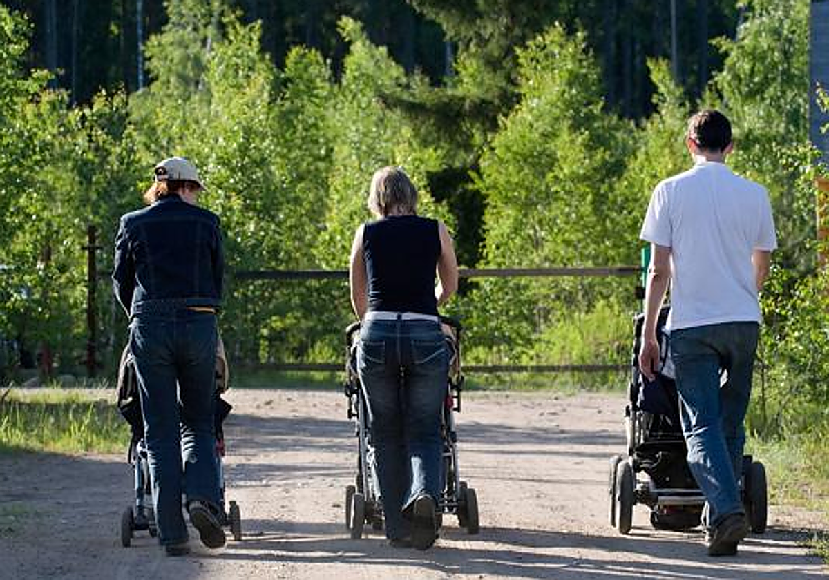 Tres padres pasean con sus hijos.