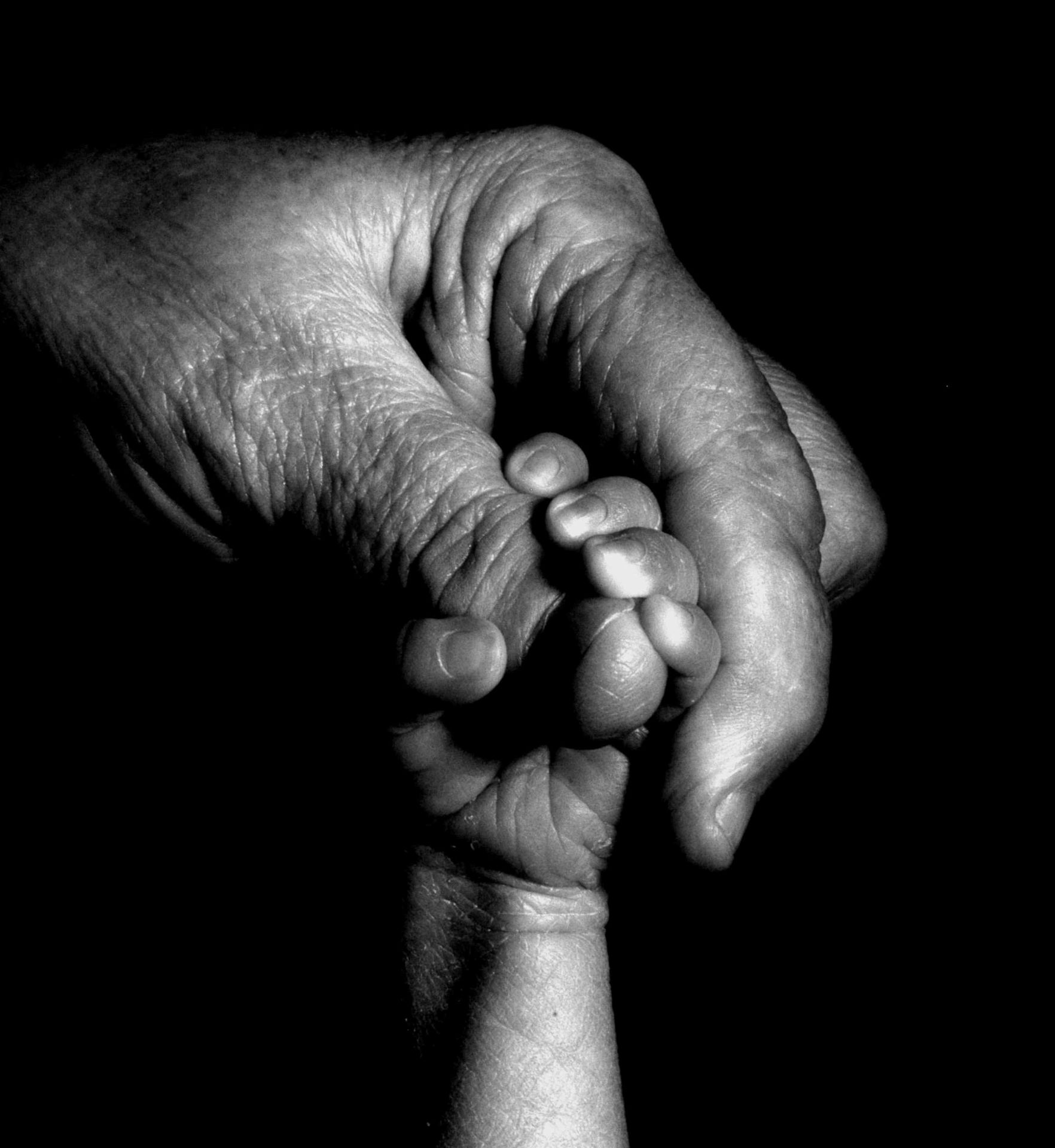 Fotografía de dos manos, una de un niño y otra de un adulto, entrelazadas