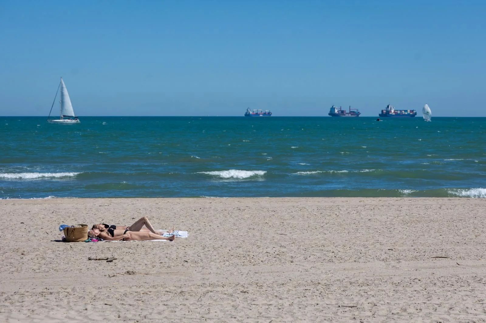 Dos mujeres toman el sol en la playa.