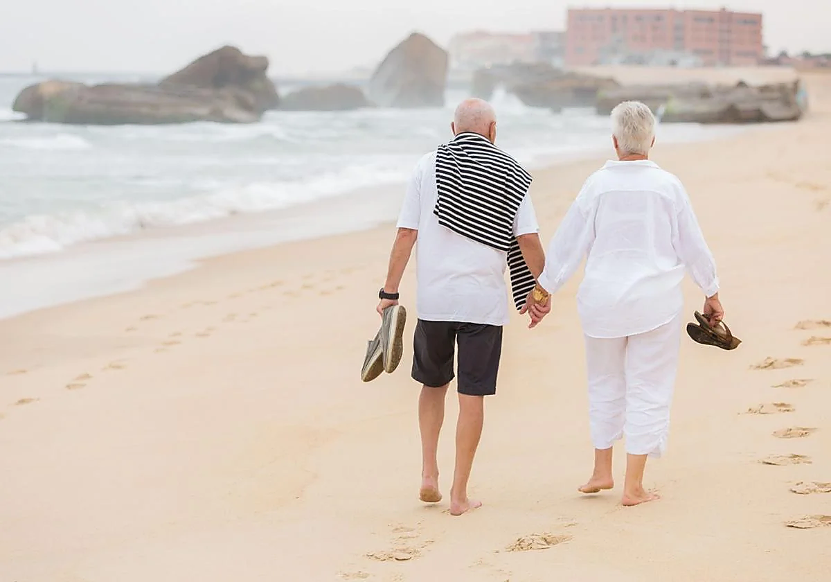 Una pareja pasea por la playa.