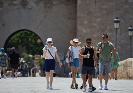 Turistas pasean por Valencia equipados con sombreros y abanicos para combatir el calor.