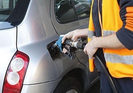 El empleado de una gasolinera echa carburante a un vehículo.