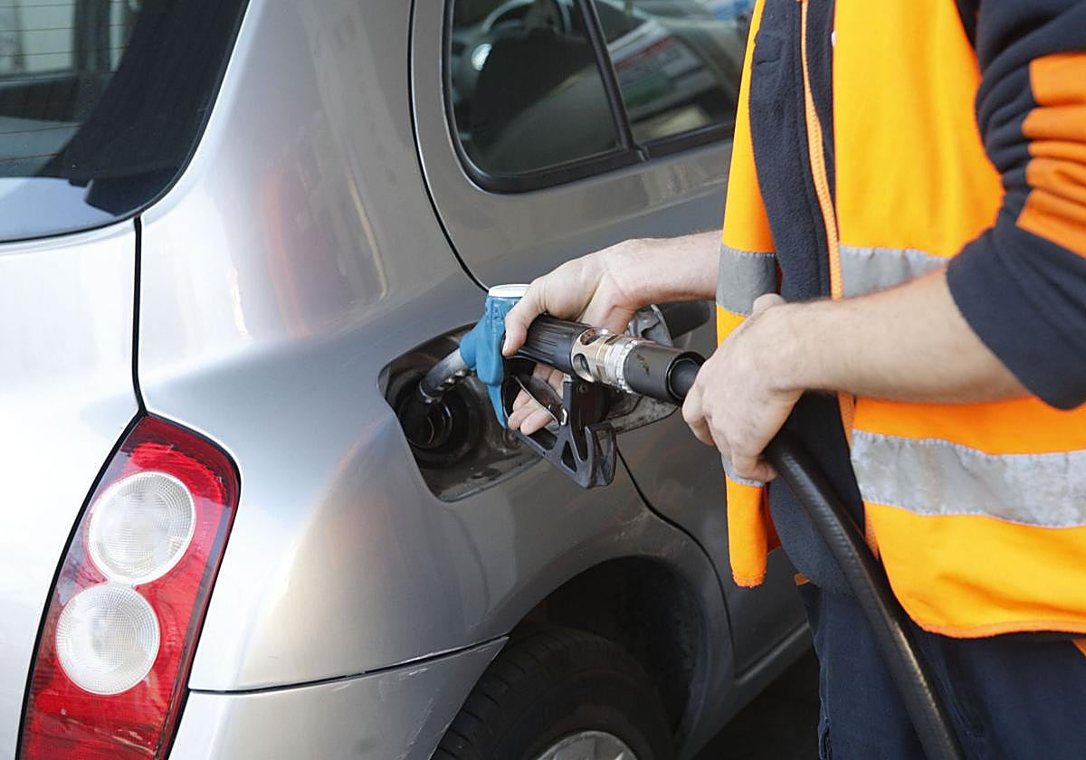 El empleado de una gasolinera echa carburante a un vehículo.