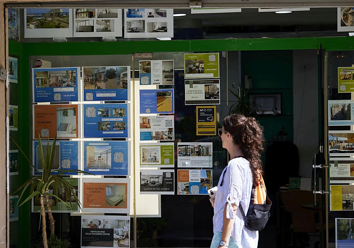 Una joven, ante el escaparate de una inmobiliaria.