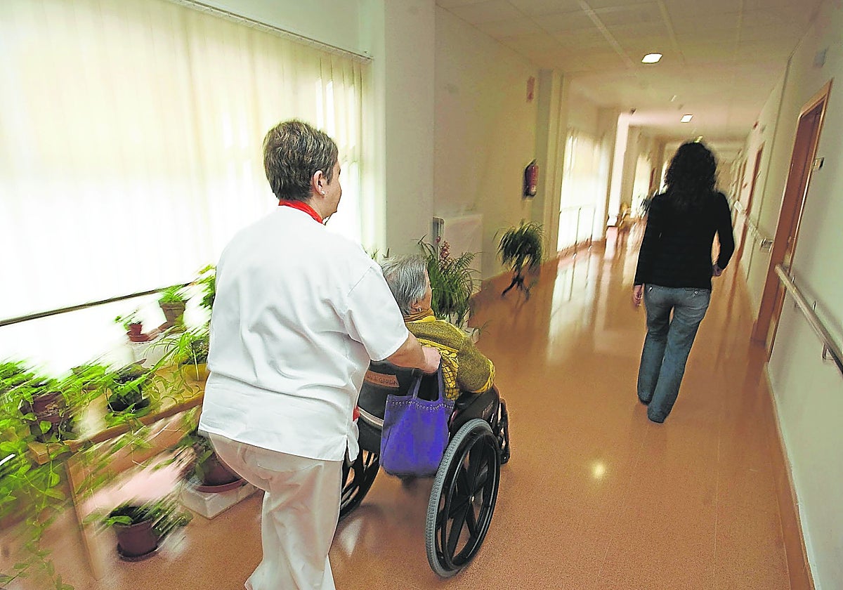 Una celadora traslada a una mujer en una residencia.