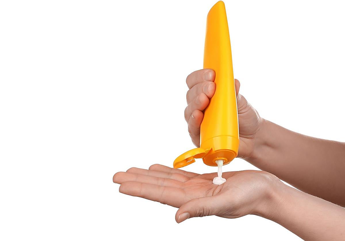 Persona aplicándose crema de solar en la mano