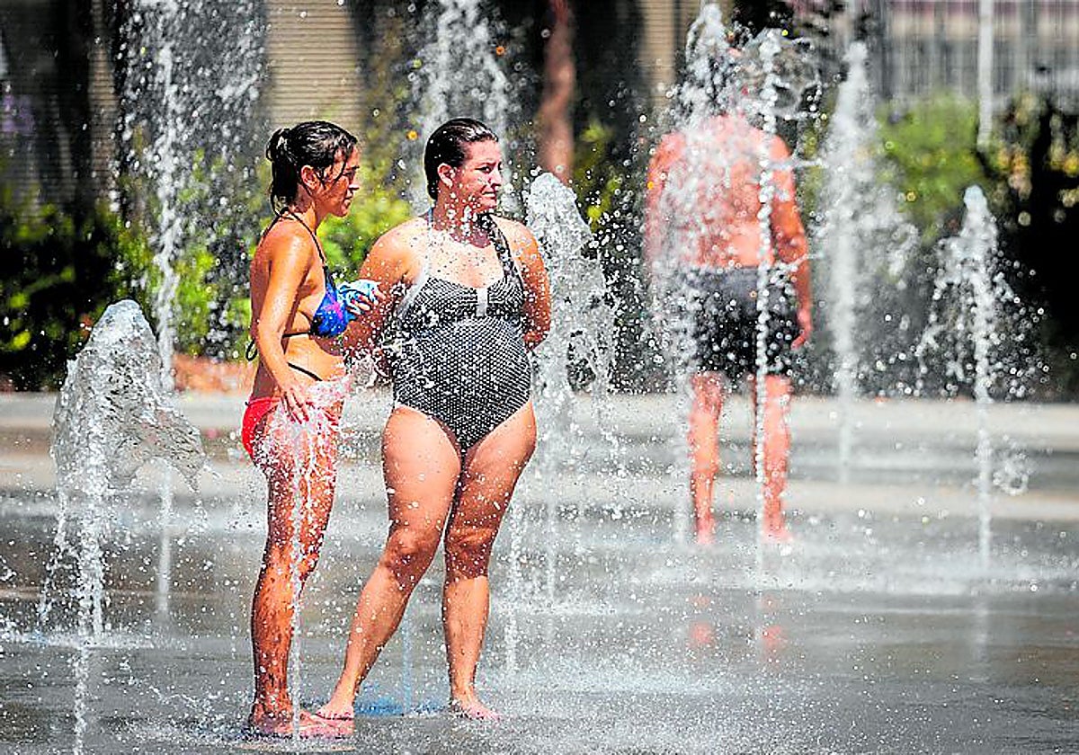 Dos mujeres se refrescan en una fuente de Valencia.