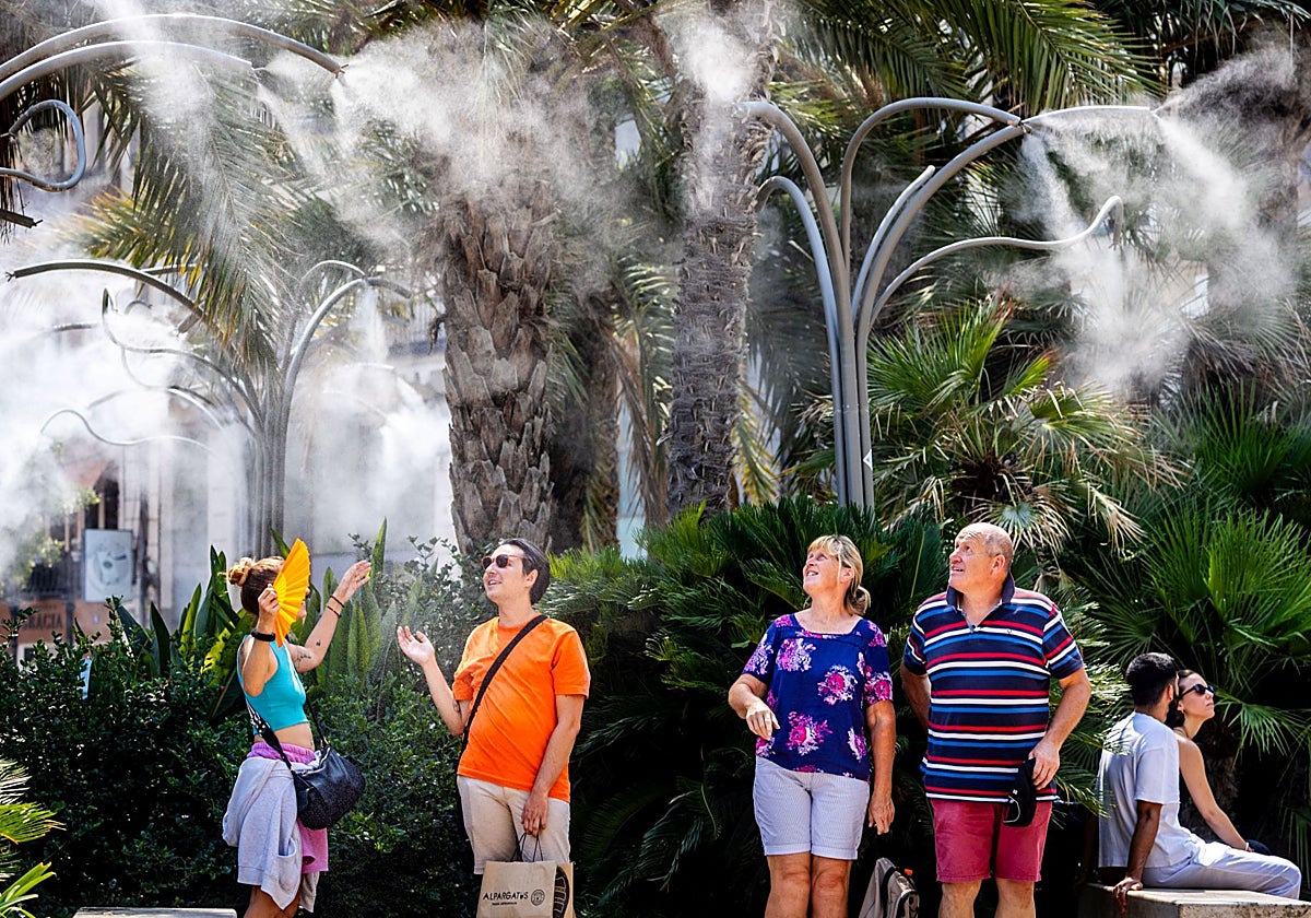 La gente se refresca en los humidificadores de la plaza de la Reina