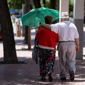 Una pareja de personas mayores pasea por un parque.