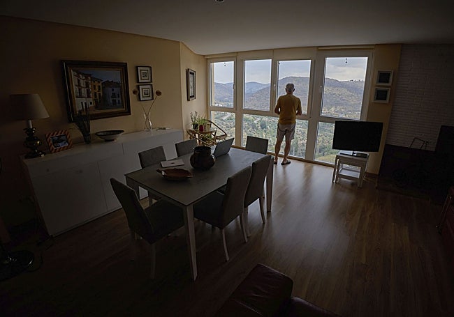 Miguel Macián mira por el ventanal de su casa reparada tras el daño del incendio.