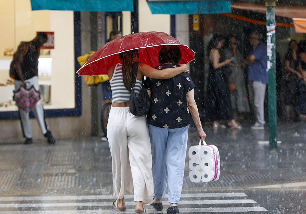 Una pareja se resguarda de las lluvias en Valencia. Imagen de archivo.