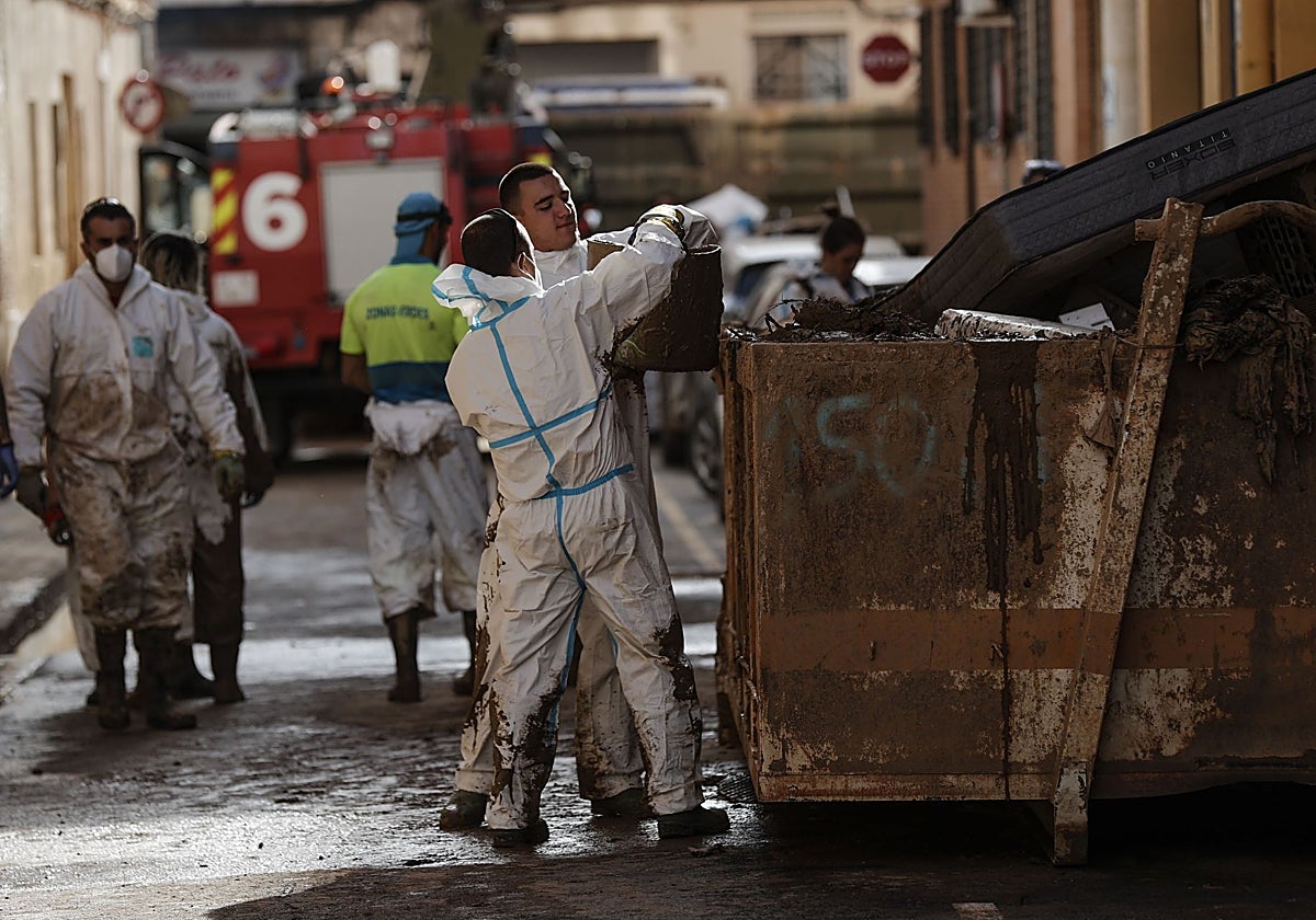 Voluntarios sacan lodo de los bajos de Paiporta.