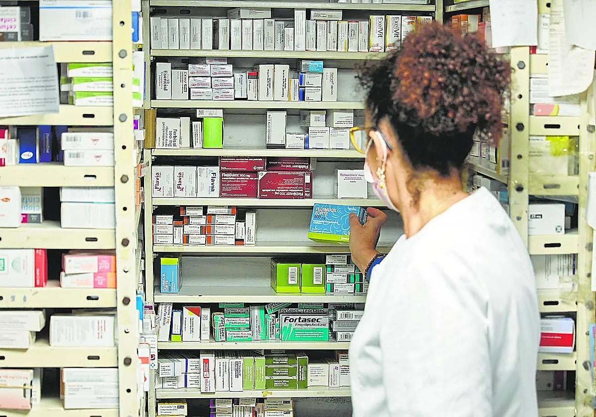 Una farmacéutica muestra huecos vacíos en sus estantes.
