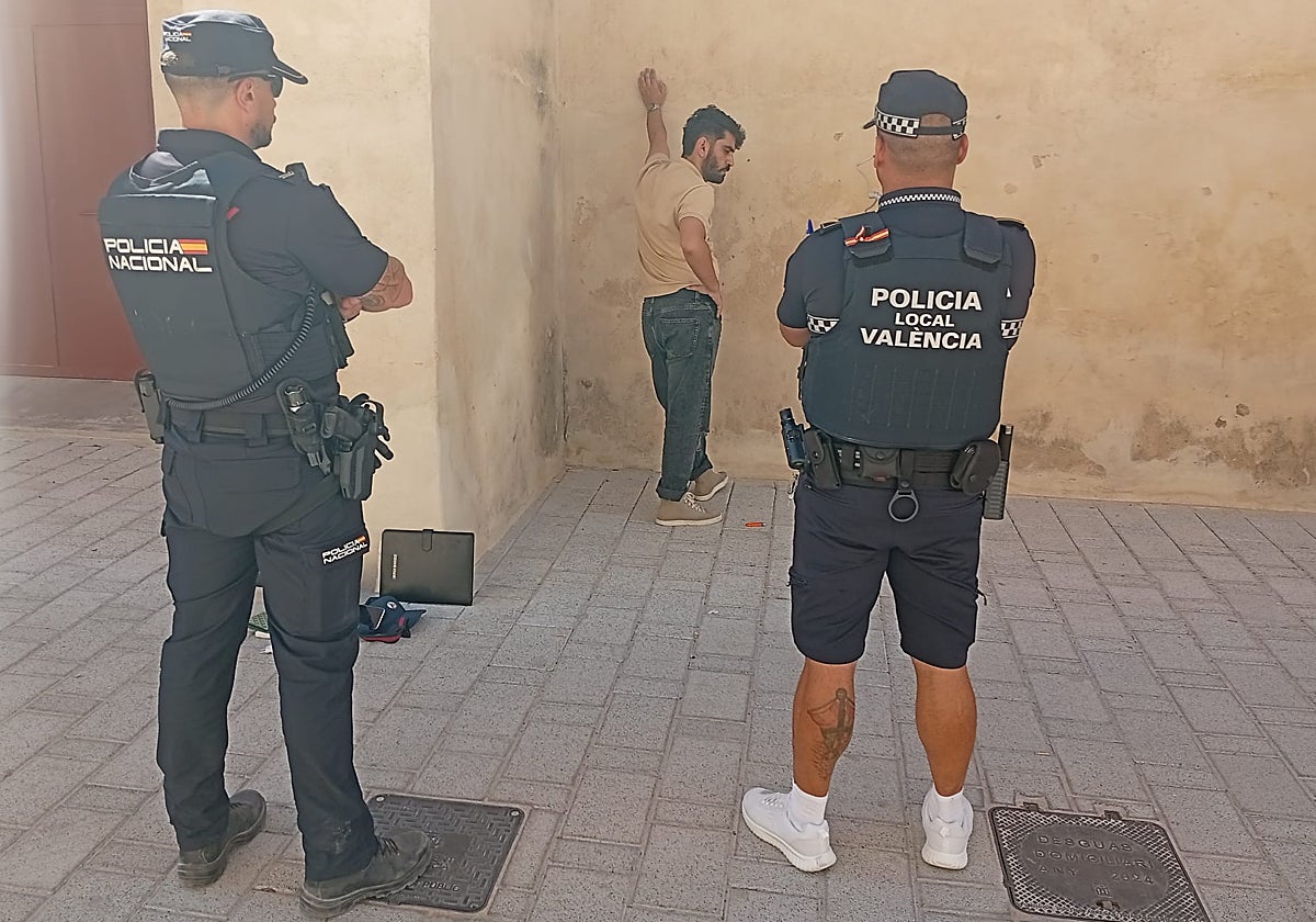 Dos policías custodian al presunto ladrón junto al muro de las atarazanas del Grao.
