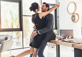 Una pareja en actitud cariñosa dentro de un despacho.