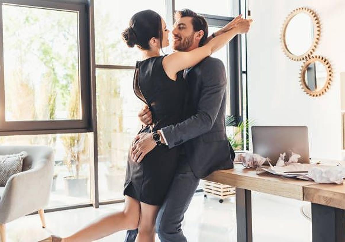 Una pareja en actitud cariñosa dentro de un despacho.