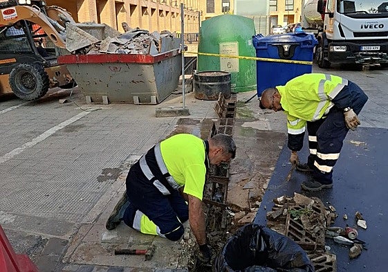 Dos operarios limpian imbornales en Catarroja antes de la temporada de lluvias.