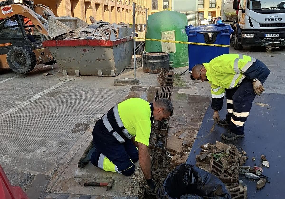 Dos operarios limpian imbornales en Catarroja antes de la temporada de lluvias.