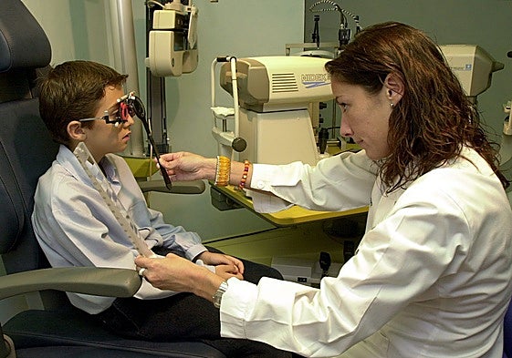 Una profesional óptica revisa la vista a un niño.