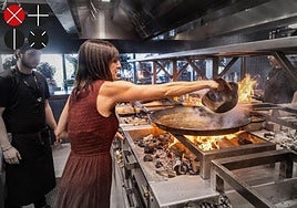 Una comensal echar el arroz a la paella en la cocina del restaurante del Roig Arena, Poble Nou.