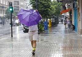 Un hombre se resguarda de la lluvia en Valencia. Imagen de archivo.