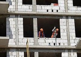 Dos obreros trabajan en la construcción de un edificio.