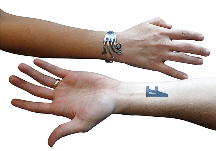 Las manos de Carito y Germán. Ella, con un tenedor que abraza su muñeca. El con la F de Fierro tatuada