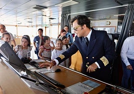 El capitán del buque Ciudad de Barcelona de Trasmed explica a las falleras el funcionamiento del barco.