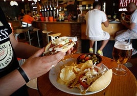 Un hombre consume bebidas y tapas en un bar, imagen de archivo.