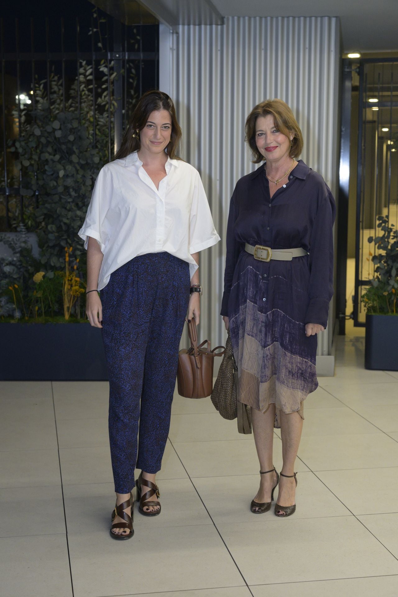 Isabel Clérigues luce pantalón y camisa blanca de seda, mientras que su madre, Isabel Aliño, se decantó por un vestido camisero y bolso de Massimo Dutti. 
