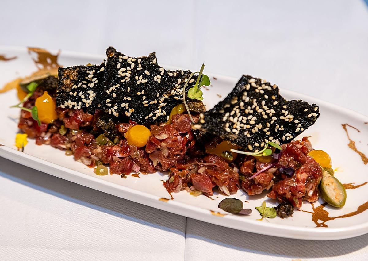 Imagen secundaria 1 - Jesús Muñoz, con la fideuà de gamba alistada y navajas. A la izquierda, steak tartar marinado en salsa kimchee, soja y aceite de oliva virgen extra, con una yema ligeramente picante y alga nori crujiente. A la derecha, ostras valencianas con emulsión de pisco sour.