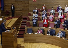 Mazón prepara los folios de su discurso en el debate de política general de la Comunitat mientras el PSPV muestra carteles sobre la dana.