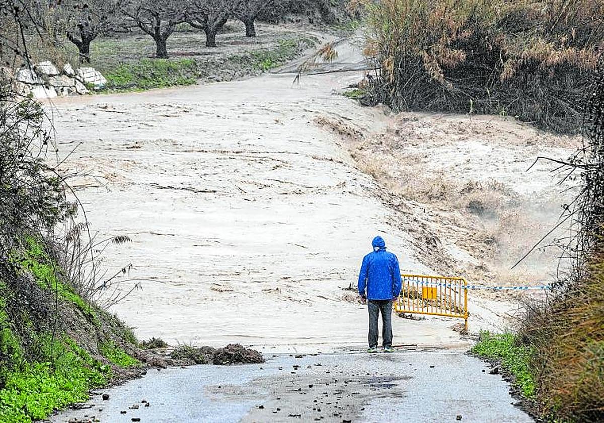 Un hombre contempla una carretera cortada por la lluvia, en una imagen de archivo.