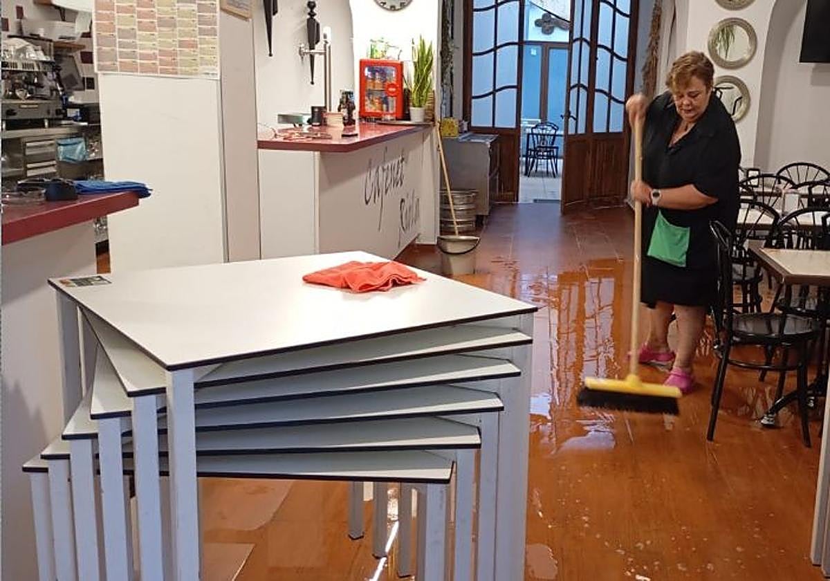 Ana limpia el agua que ha entrado en su bar de Paiporta.