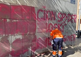 Operarios del Ayuntamiento limpiando la pintada encontrada junto a la Ciudad de la Justicia de Valencia.