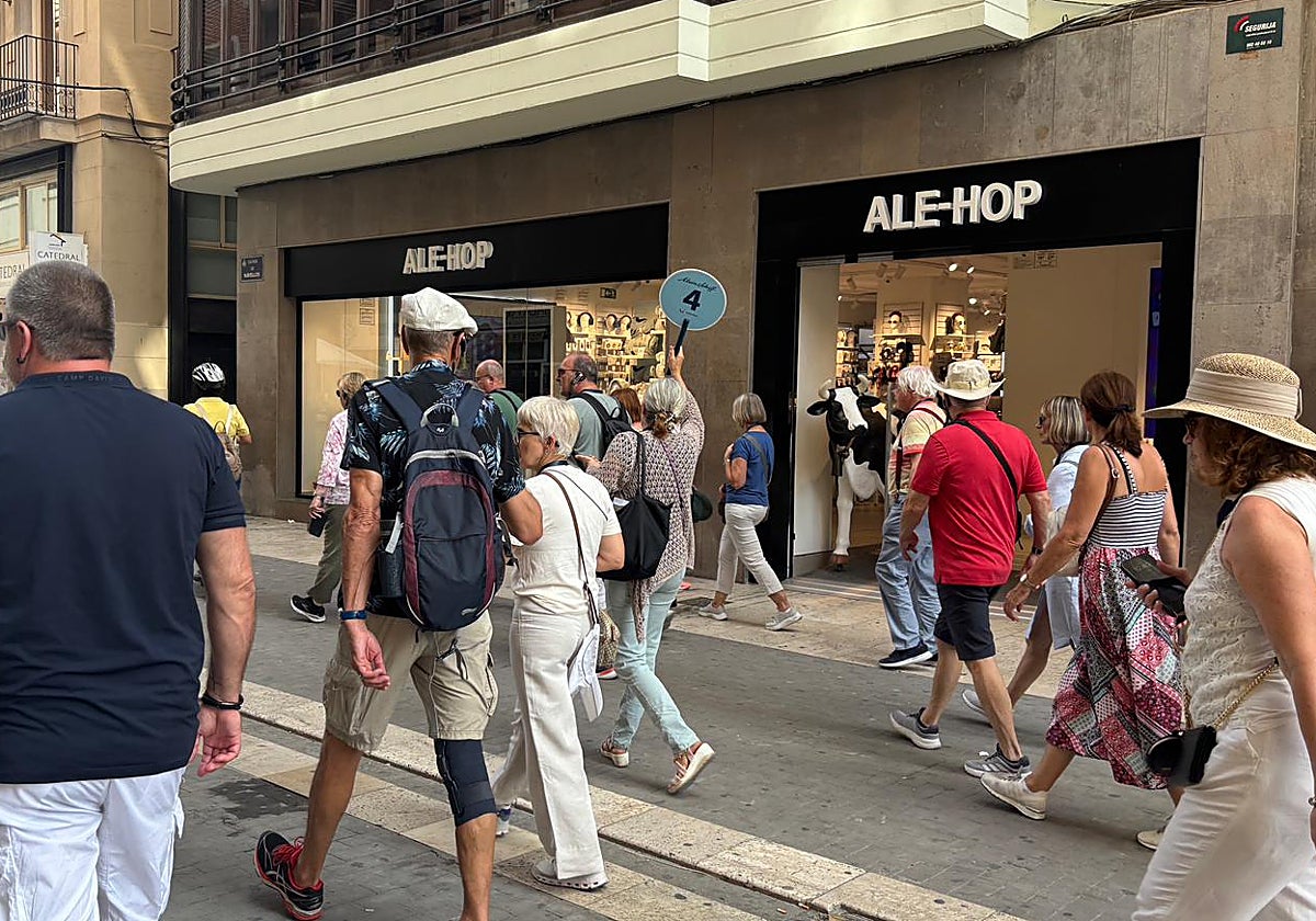Un grupo de turistas sigue a un guía por la calle Navellos, este jueves.