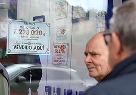 Una administración de Loterías y Apuestas del Estado cuelga el cartel de un premio.