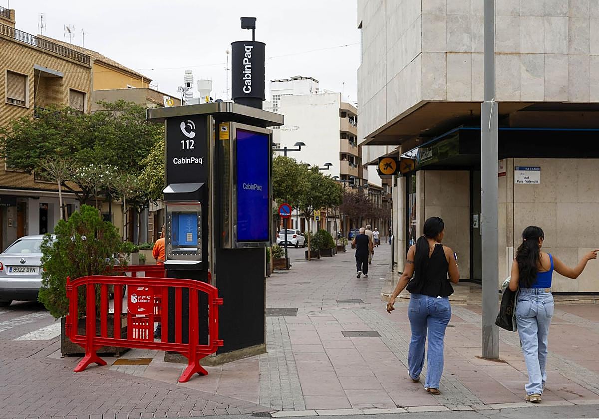 Dos jóvenes pasan junto a una de las cabinas instaladas en Alaquàs.