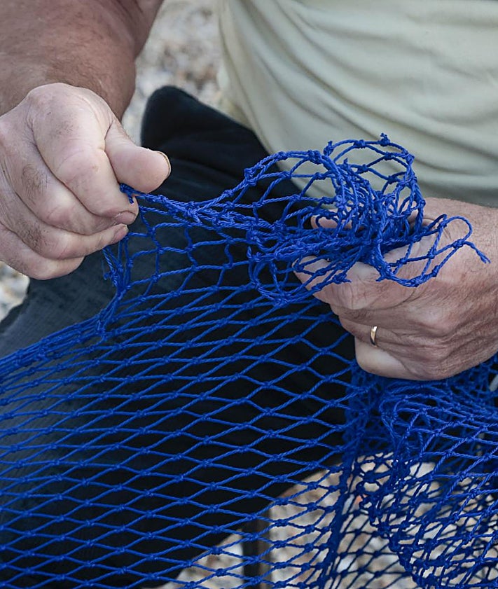 Imagen secundaria 2 - Lluís Marco y Carmen Serrano integran una de los tres matrimonios que mantienen viva la pesca en el punto de la Goladel Pujol. Operarios seleccionan capturas en la lonja. Lluís preparando las redes para atrapar cangrejo azul.