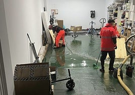 Bomberos trabajan achicando agua en uno de los garajes inundados en Alcàsser.