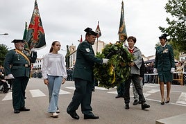 María Isabel y uno de sus dos nietos coloca la corona floral en homenaje a los caídos en los actos de la Guardia Civil en Utiel.
